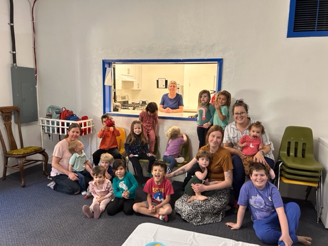 Caregivers and young children gathered together at a Mother Goose group session